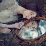 donna giovane e bella che si guarda in uno specchio dorato