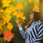 Una donna contempla le foglie che cadono dagli alberi