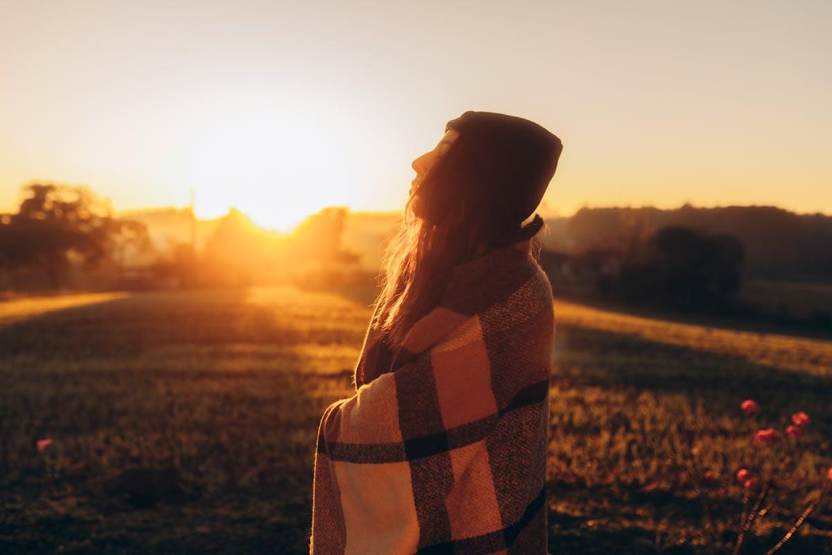 Una donna saluta il sole all'alba
