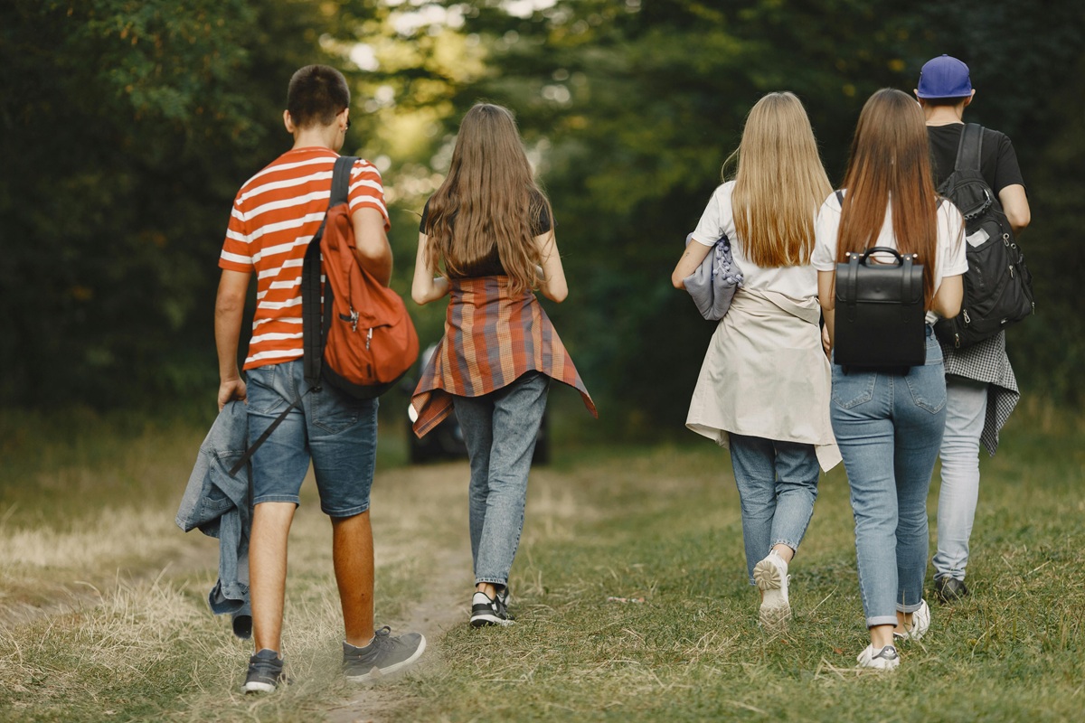 ragazzi che camminano tra gli alberi di spalle