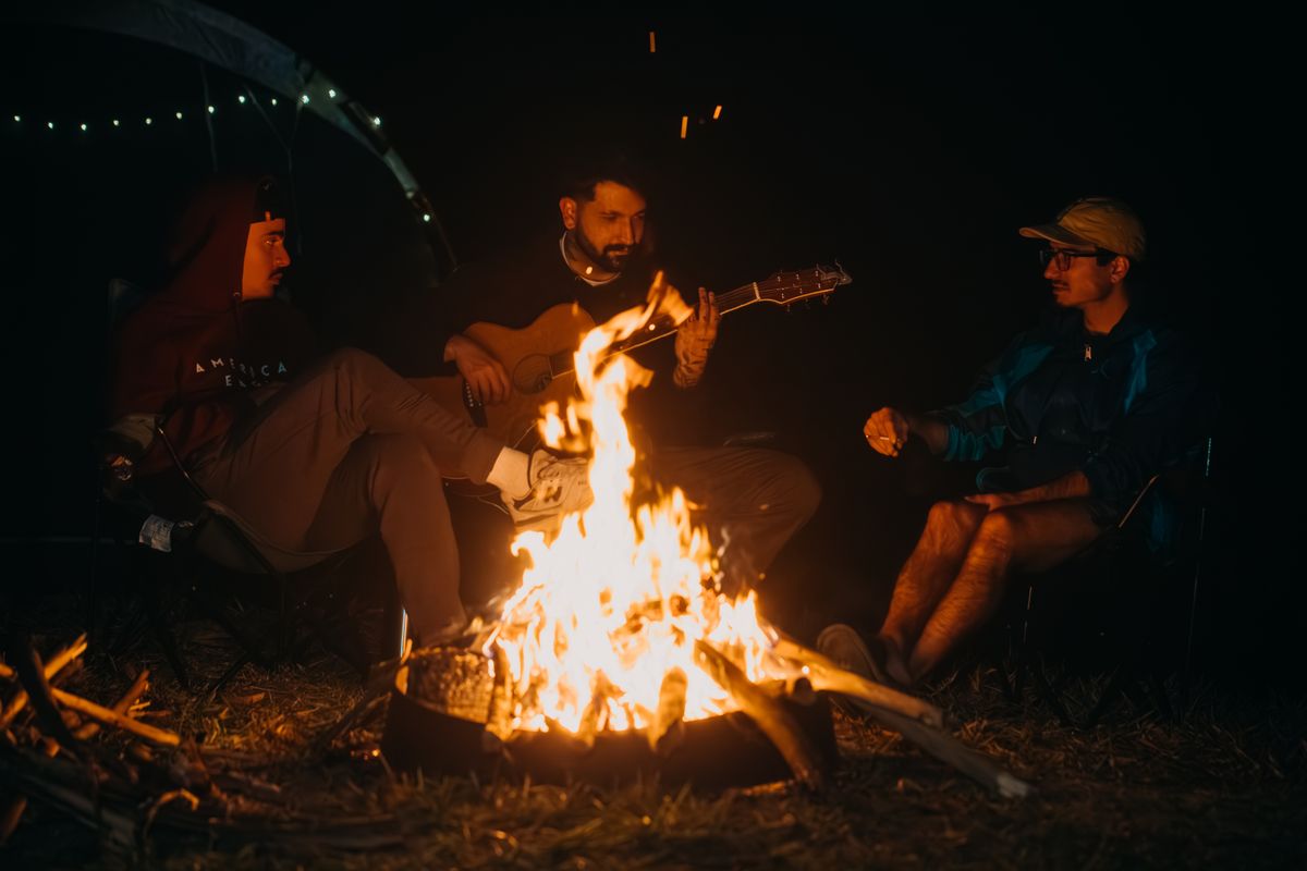 Gruppo di persone riunite intorno a un falò, simbolo della dimensione comunitaria dei rituali di passaggio
