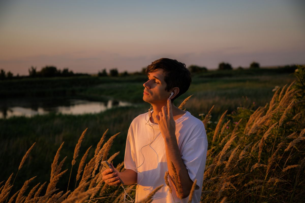 Giovane uomo ascolta musica in natura