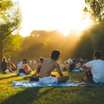 Persone che si godono una giornata di sole con picnic in un parco verde, catturando l'atmosfera estiva di ferragosto.