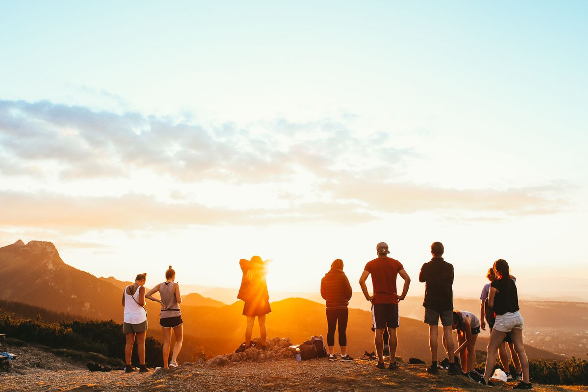 Un gruppo di amici che osserva un bellissimo tramonto su una montagna per celebrare il 15 agosto.