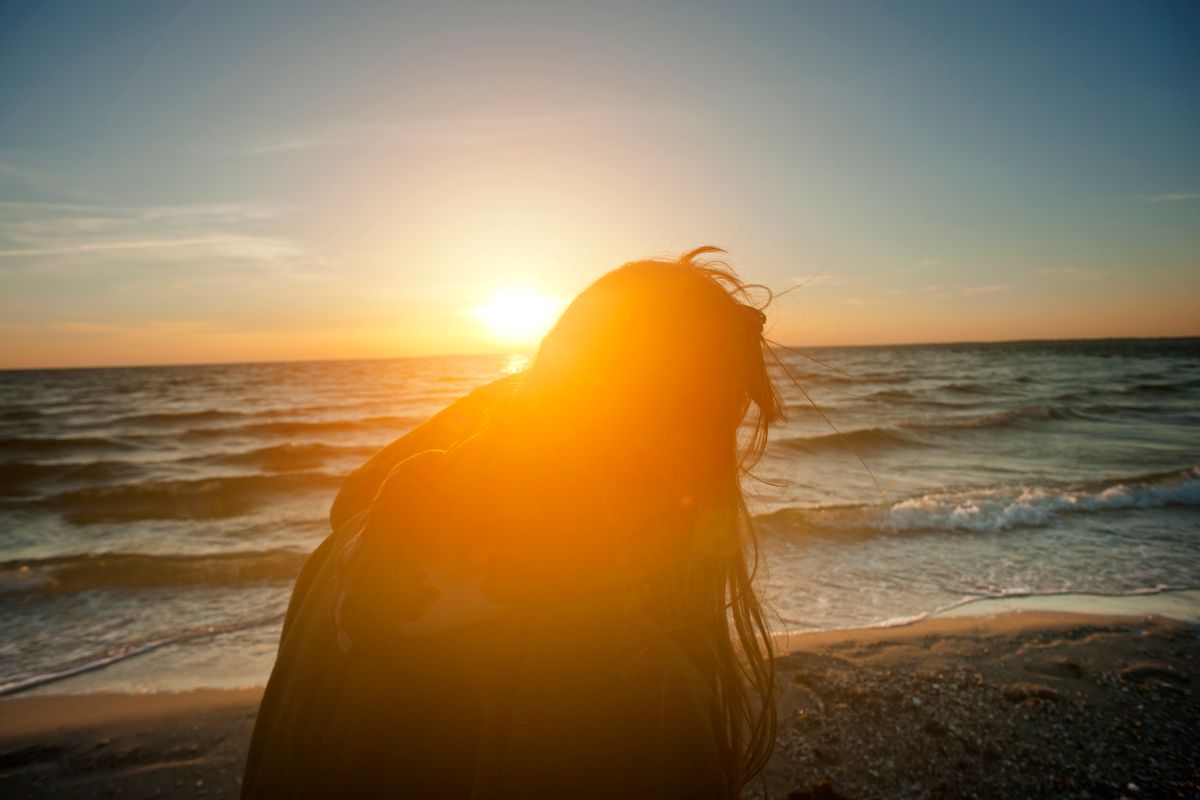Una donna in spiaggia illuminata dal sole, simbolo di coscienza
