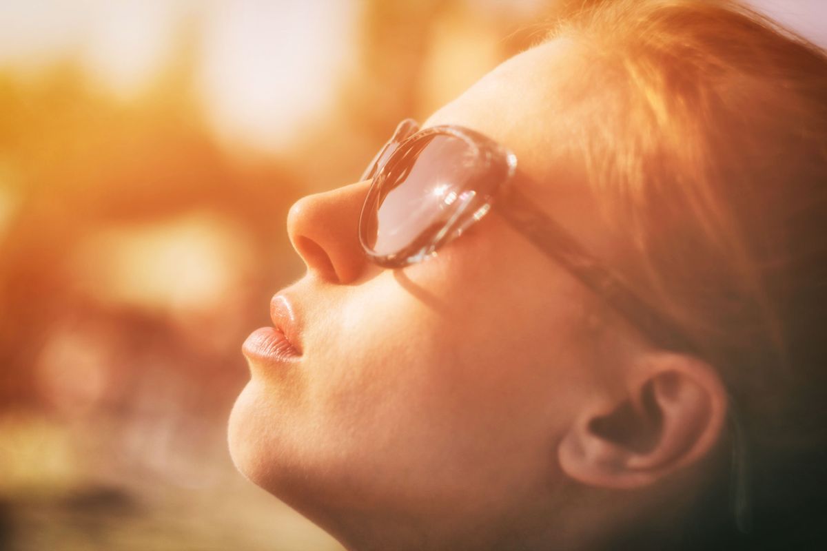 Una donna in spiaggia illuminata dal sole, simbolo di coscienza