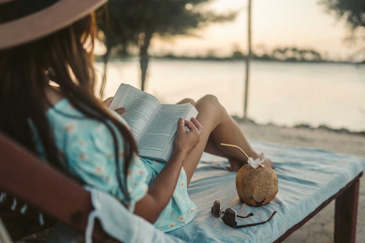 donna si rilassa con libro in riva al mare