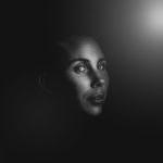 viso di donna al buio con uno spiraglio di luce che lo illumina