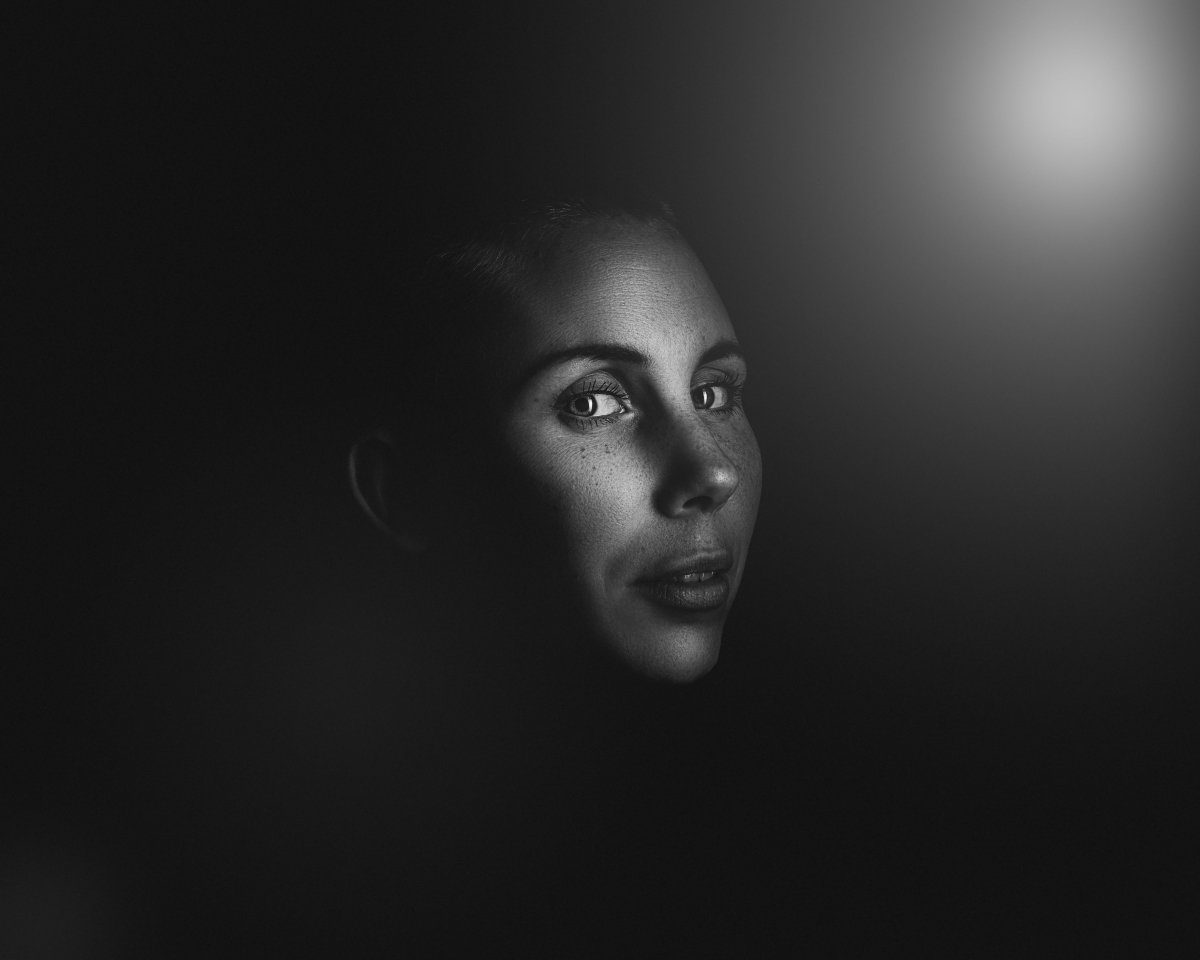 viso di donna al buio con uno spiraglio di luce che lo illumina
